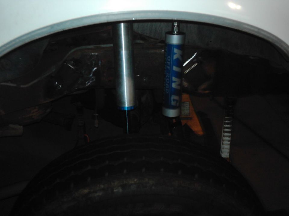 Close-up of rear suspension components, including two shock absorbers, one labeled KING OFF ROAD, and a tire