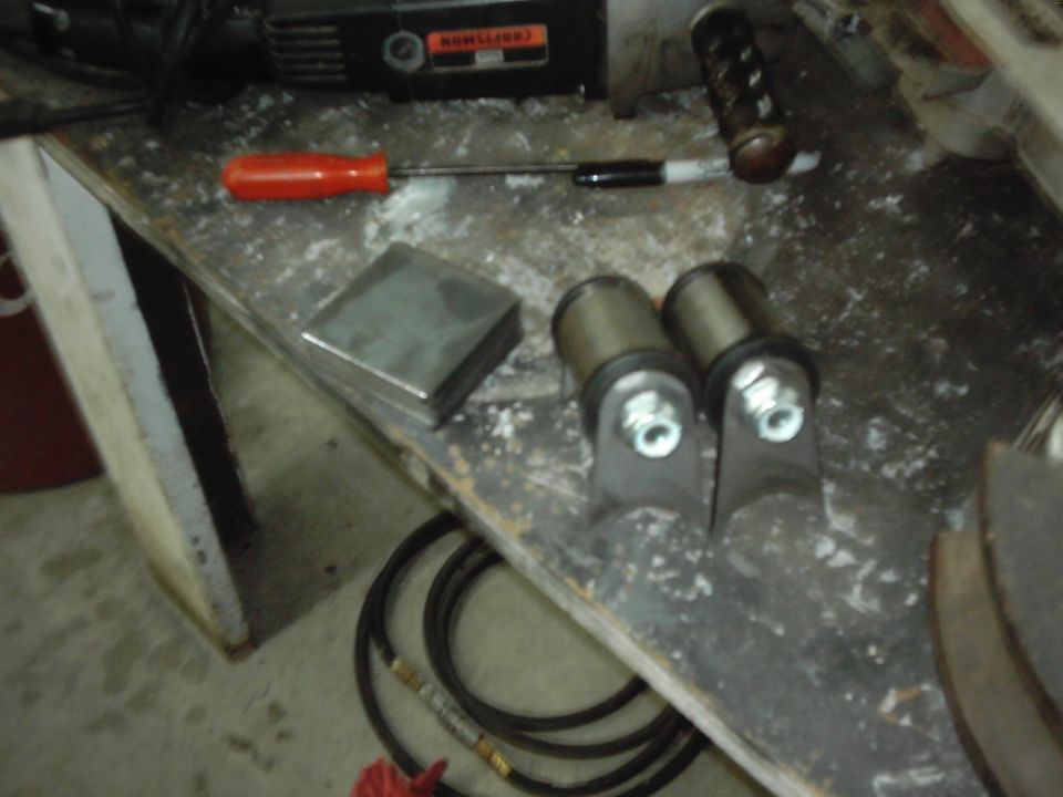 Workbench with a Craftsman grinder, screwdriver, metal block, and two suspension bushings