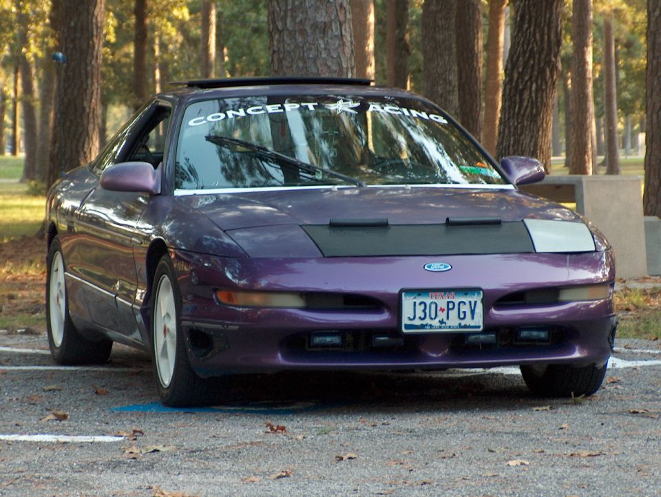 Purple Ford Probe with a black car bra and a "CONCEPT RACING" banner on the windshield
