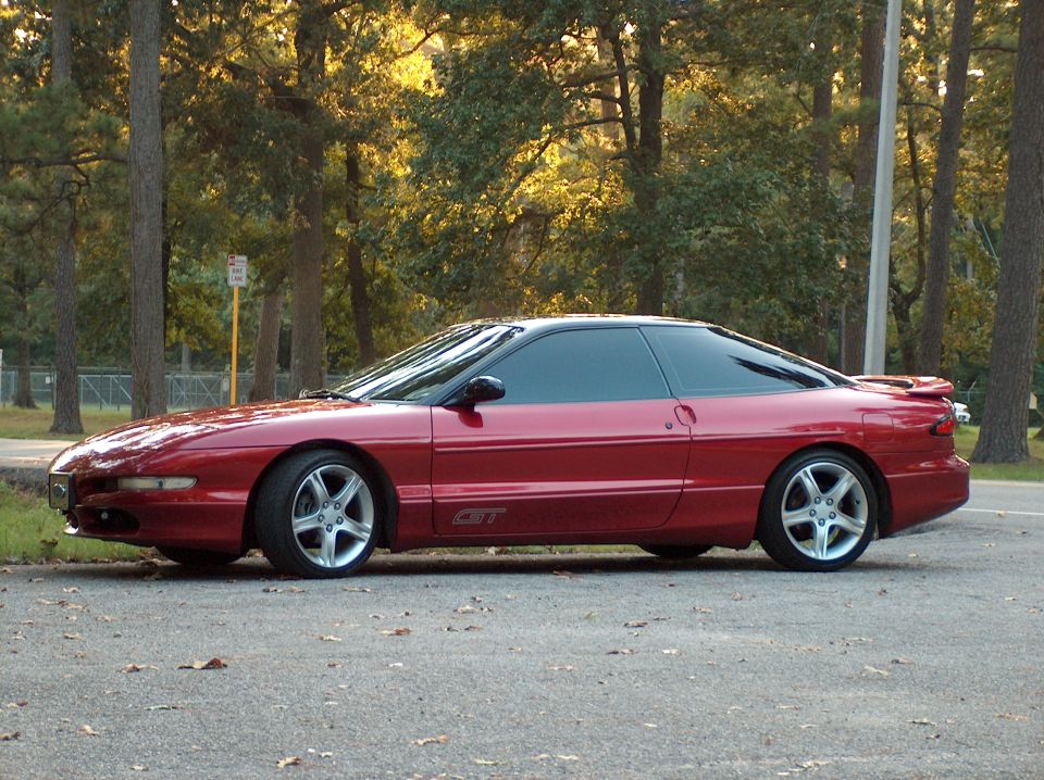 Red coupe with a black roof and tinted windows parked on asphalt