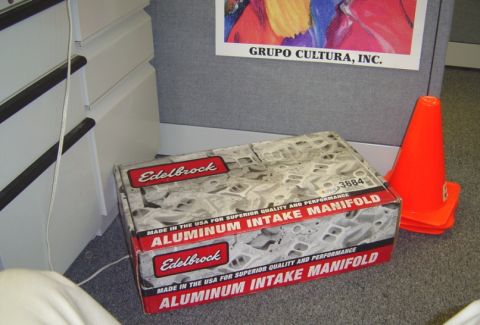1986 Ford Bronco - Boxed Edelbrock aluminum intake manifold, part number 3884, sits on the floor next to orange cones.