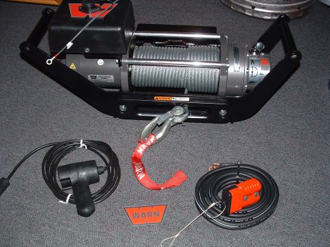 1993 Ford Bronco - Warn winch and its associated wiring and hook are laid out on a carpeted surface.