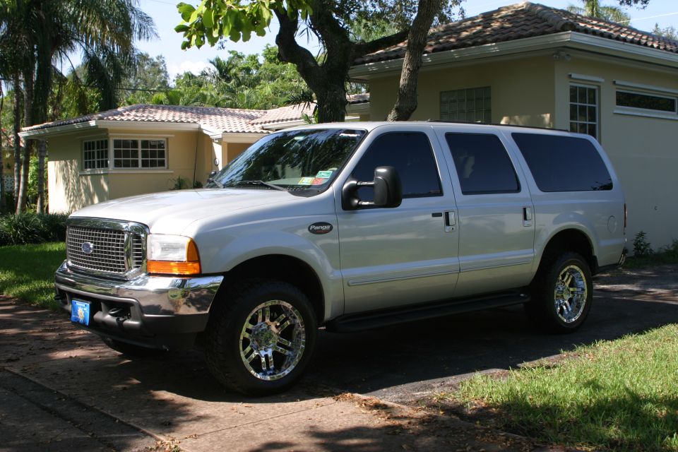 Silver Ford Excursion SUV on a driveway with chrome wheels and tinted rear windows