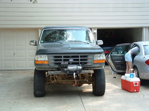 1993 Ford Bronco - Front view of a 1993 Ford Bronco equipped with a winch, parked in front of a garage.