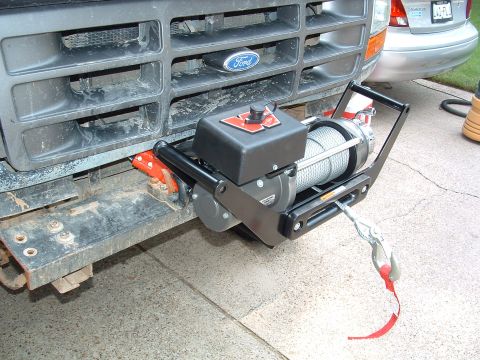 1993 Ford Bronco - Front view of a winch installed on a Ford truck's grille guard, with another vehicle in the background.