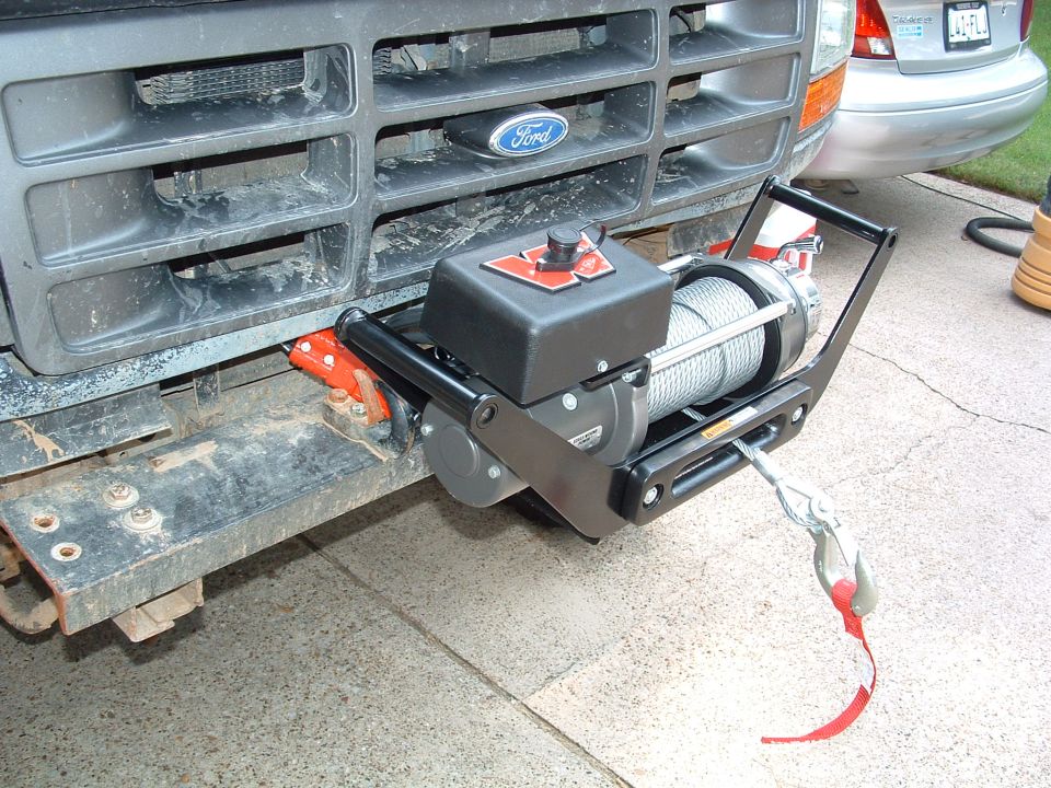 Winch mounted on a 1992 Ford truck's grille guard. Another vehicle is visible behind