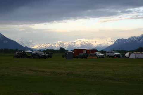 2003 Jeep TJ - A group camping scene with multiple vehicles and tents set against a backdrop of mountains.