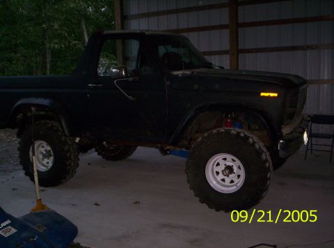 1985 Ford Bronco - This dark SUV, likely from the 1980s, is modified with a lift kit and oversized tires.