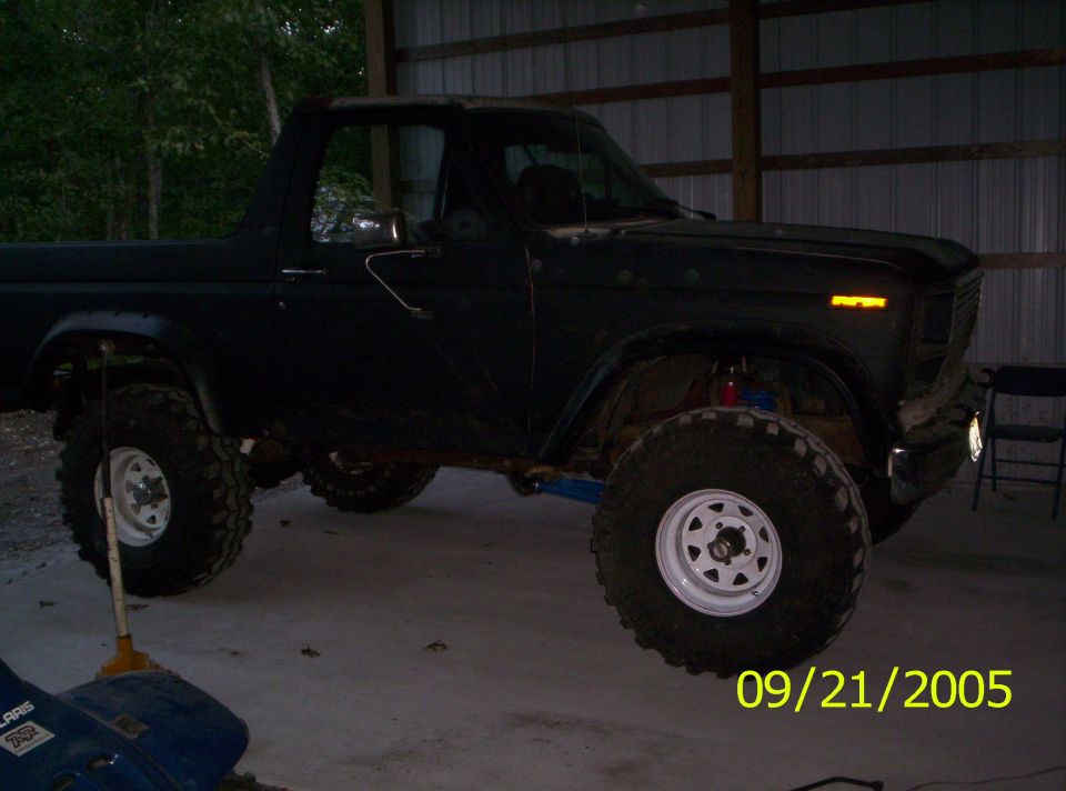 Dark SUV with lifted suspension and large off-road tires, parked indoors