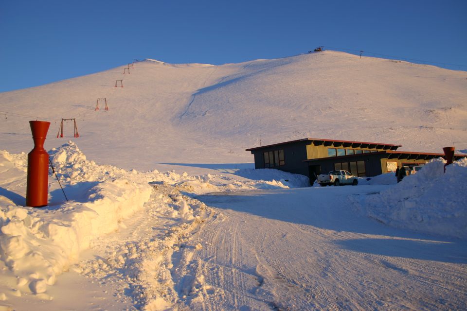Snowy mountain landscape with a building and ski lift towers under a clear blue sky