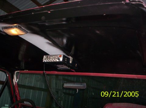 1985 Ford Bronco - A CB radio is mounted to the headliner of a vehicle's interior, with a rearview mirror visible.
