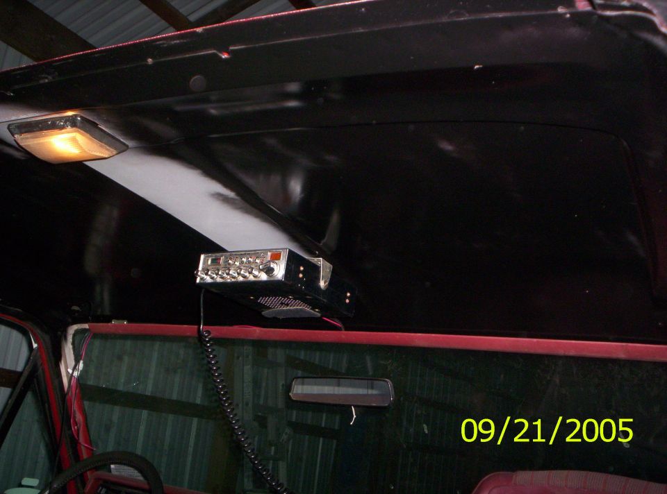 Interior view of a vehicle's headliner with a CB radio mounted and a rearview mirror