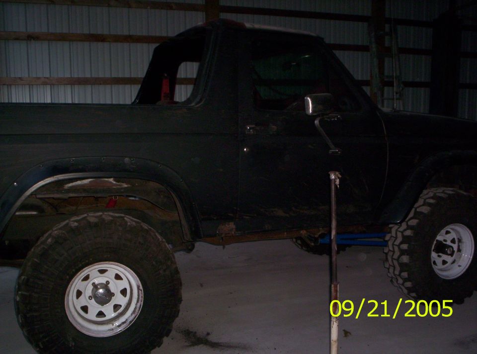 Black Ford Bronco with lifted suspension and large tires, seen from the side in a garage
