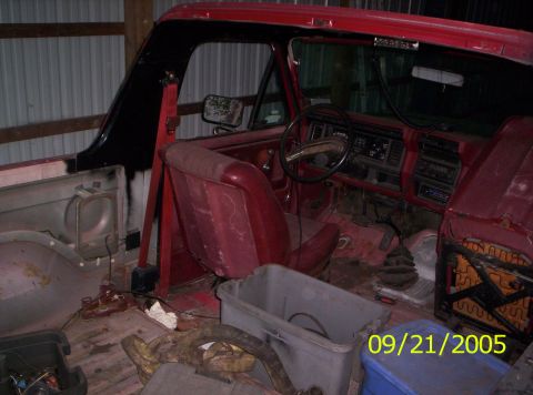 1985 Ford Bronco - Interior view of a red SUV, showing its dashboard, seats, and floor, with a storage bin present.