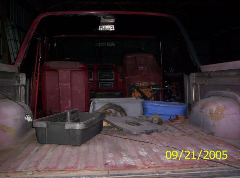 1985 Ford Bronco - Interior view of a red Ford Bronco, showing seats and cargo area filled with items.