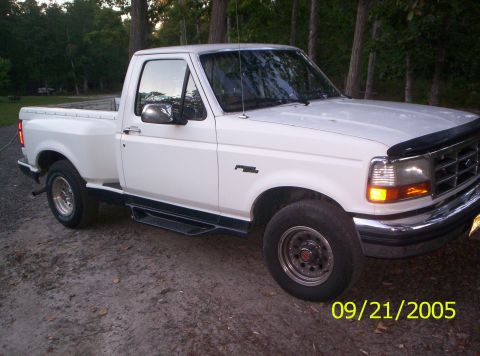 1985 Ford Bronco - This white Ford F-150 pickup truck is shown from a 3/4 front angle.