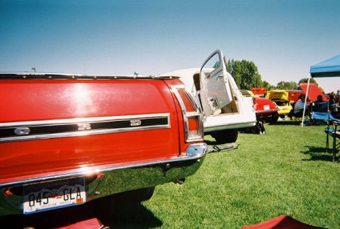 1972 Ford Ranchero - A red Ford Ranchero is parked on grass with other vehicles and people around it on a sunny day.