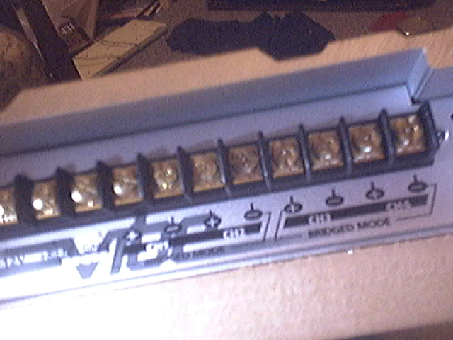 Close-up of an audio amplifier's screw terminal block with labels for "BRIDGED MODE"