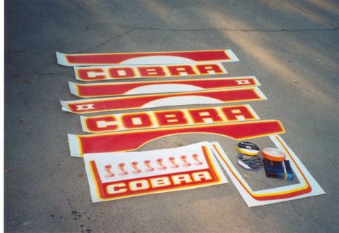 1978 Ford Mustang II - Various Cobra decals and trim pieces are laid out on the ground, along with some adhesive supplies.