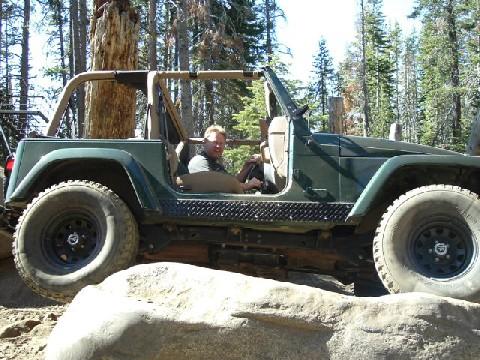 1996 Ford Bronco - A green Jeep Wrangler navigates rocky terrain with a driver behind the wheel.