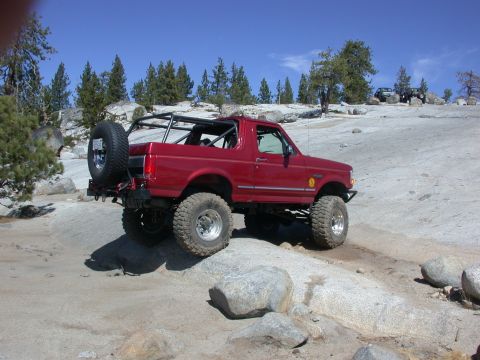 1996 Ford Bronco - This red 1996 Ford Bronco navigates a rocky terrain, its off-road capabilities with a rear-mounted spare tire.