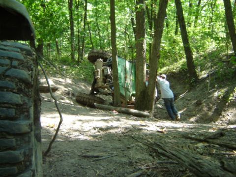 1992 Ford Bronco - A vehicle has tipped over on a wooded trail, with a person attempting to right it.