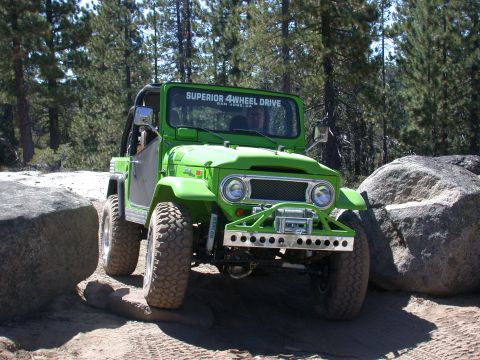1996 Ford Bronco - This modified off-road vehicle is shown navigating a rocky trail, with "SUPERIOR 4 WHEEL DRIVE" visible on the windshield.