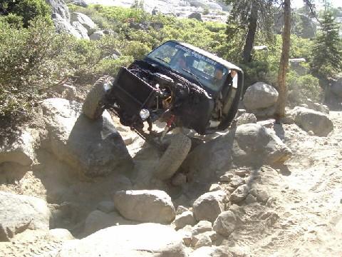1996 Ford Bronco - Off-road vehicle navigating a challenging rocky trail with its hood open.