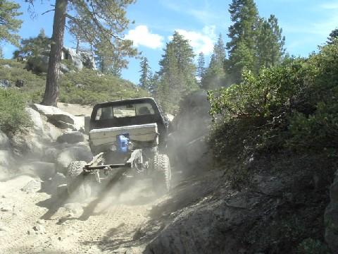 1996 Ford Bronco - A modified truck navigates a challenging, dusty off-road path with steep, rocky inclines.