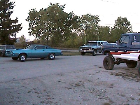 1977 Ford F-150 - A blue coupe with a black vinyl top is parked in a lot with other vehicles.