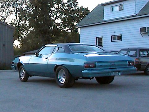 1977 Ford F-150 - A two-tone blue 1977 Ford Gran Torino coupe is viewed from the rear quarter angle in a driveway next to a house.