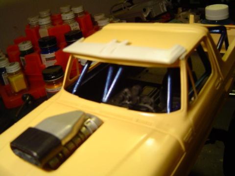 1979 Ford Bronco - A model truck build is shown with a roll cage and aftermarket hood scoop, surrounded by hobby paints.