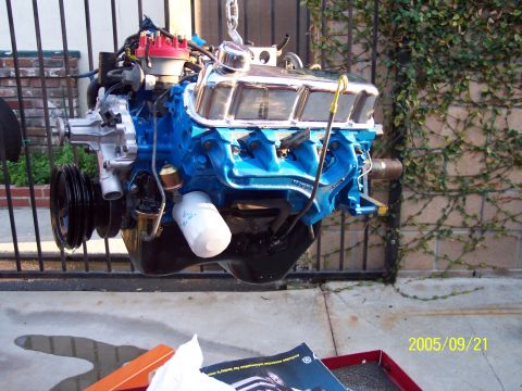 1985 Ford Bronco - Engine assembly, likely a V8, painted blue with chrome valve covers, is being worked on.