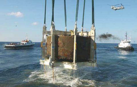1988 Ford Bronco - A large concrete block is lifted by a crane over the ocean, with boats and a helicopter in the background.