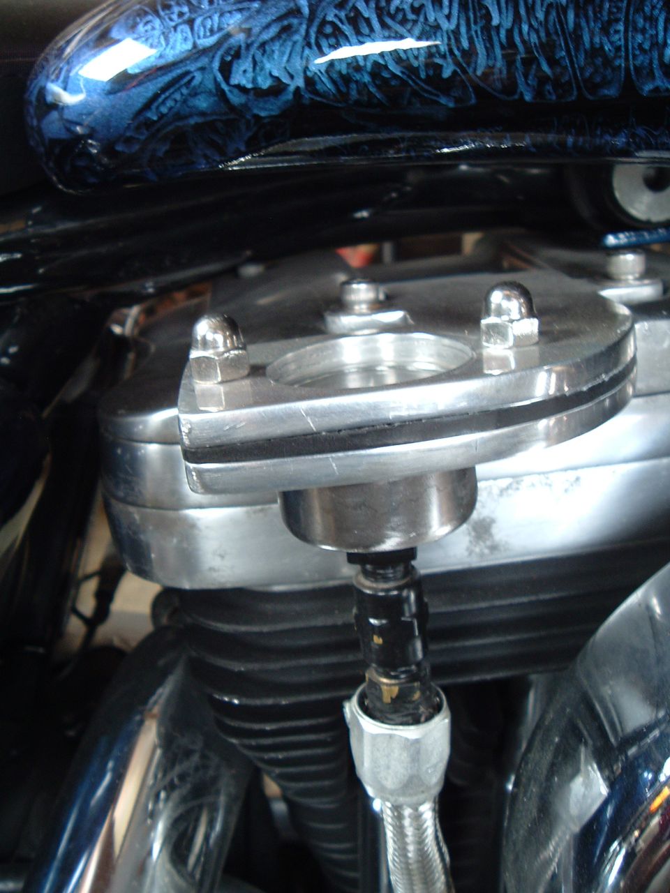 Polished rocker box on a V-twin motorcycle engine with braided stainless oil line fitting