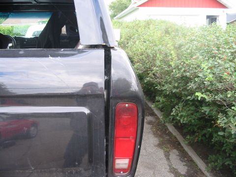 1985 Ford Bronco - Rear view of a dark gray 1978 Ford Bronco, with visible scratches on the body and a reflection of another vehicle.