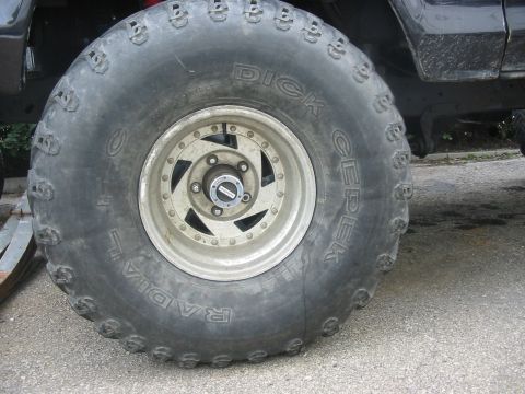 1985 Ford Bronco - A close-up view focuses on the aggressive tread of a large off-road tire and its custom wheel.