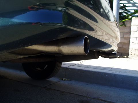 1993 Ford Taurus - The rear section of a dark green vehicle, showing the exhaust pipe and a tire.