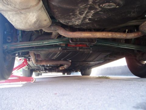 1993 Ford Taurus - The underside of a vehicle, focusing on the exhaust pipes and muffler system, with a red jack visible.