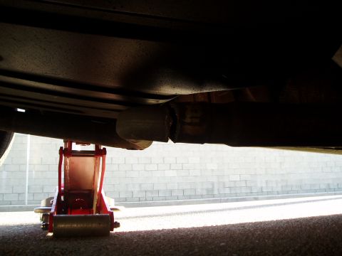 1993 Ford Taurus - A vehicle's exhaust pipe is shown broken while supported by a red jack.