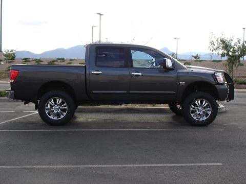 2005 Nissan Titan - This lifted pickup truck, identified as a 2005 Nissan Titan, is shown in a side profile view with chrome wheels.