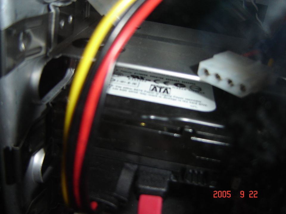 Computer hard drive with red, yellow, and black cables attached. A white connector is visible