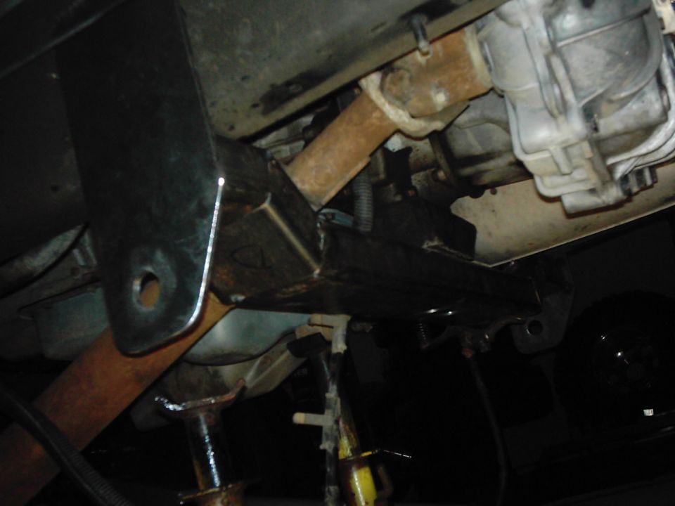 Undercarriage of a vehicle with rust on the driveshaft and frame, supported by jack stands