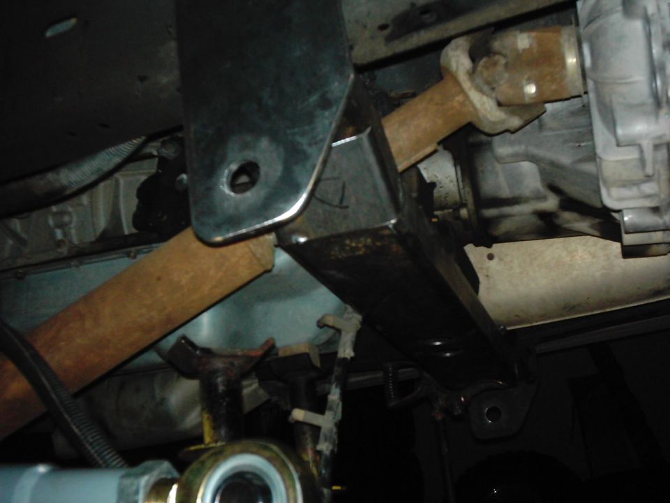 Close-up of vehicle undercarriage showing driveshaft, U-joint, and suspension bracket