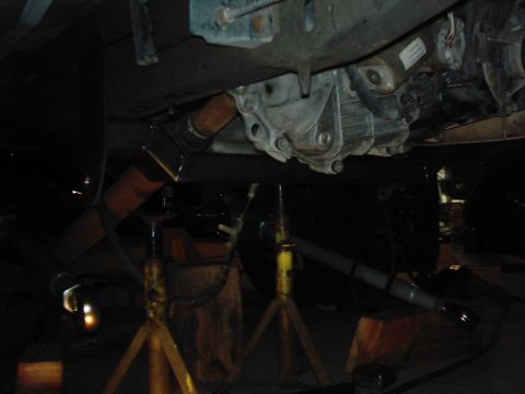 1978 Ford Bronco - The vehicle's undercarriage is visible, supported by jack stands, with the transmission and exhaust system in view.