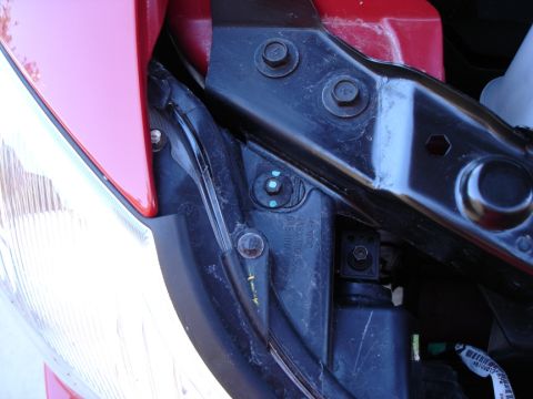 2005 Nissan Titan - Close-up view of a vehicle's headlight mounting hardware, showing bolts and wiring harness.