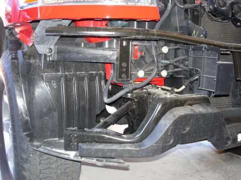 2005 Nissan Titan - The front end structure of a red vehicle is visible, showing disassembled components and wiring.