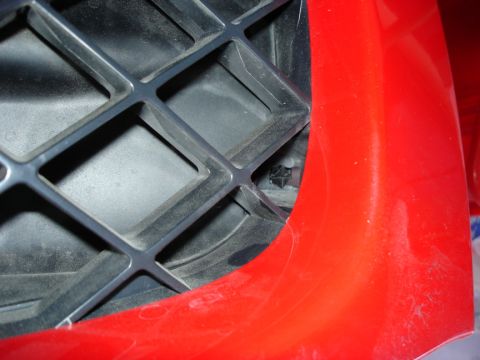 2005 Nissan Titan - Detail of a vehicle's front grille and red bumper section.