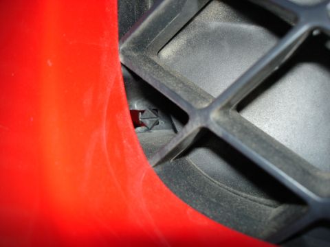2005 Nissan Titan - Detail of a vehicle's grille and surrounding red body panel, with a Supermotors logo visible.