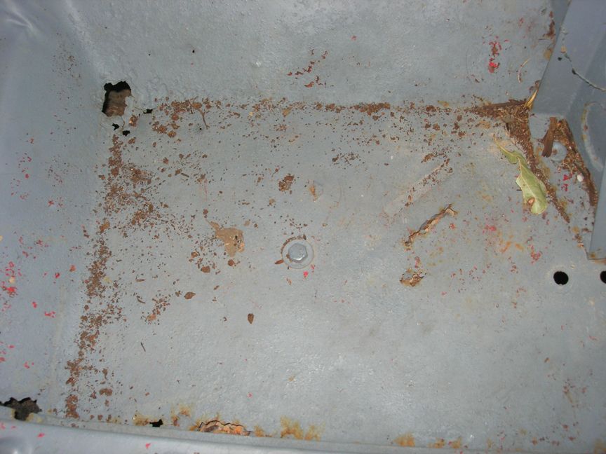 Rusted metal floor pan with holes and debris